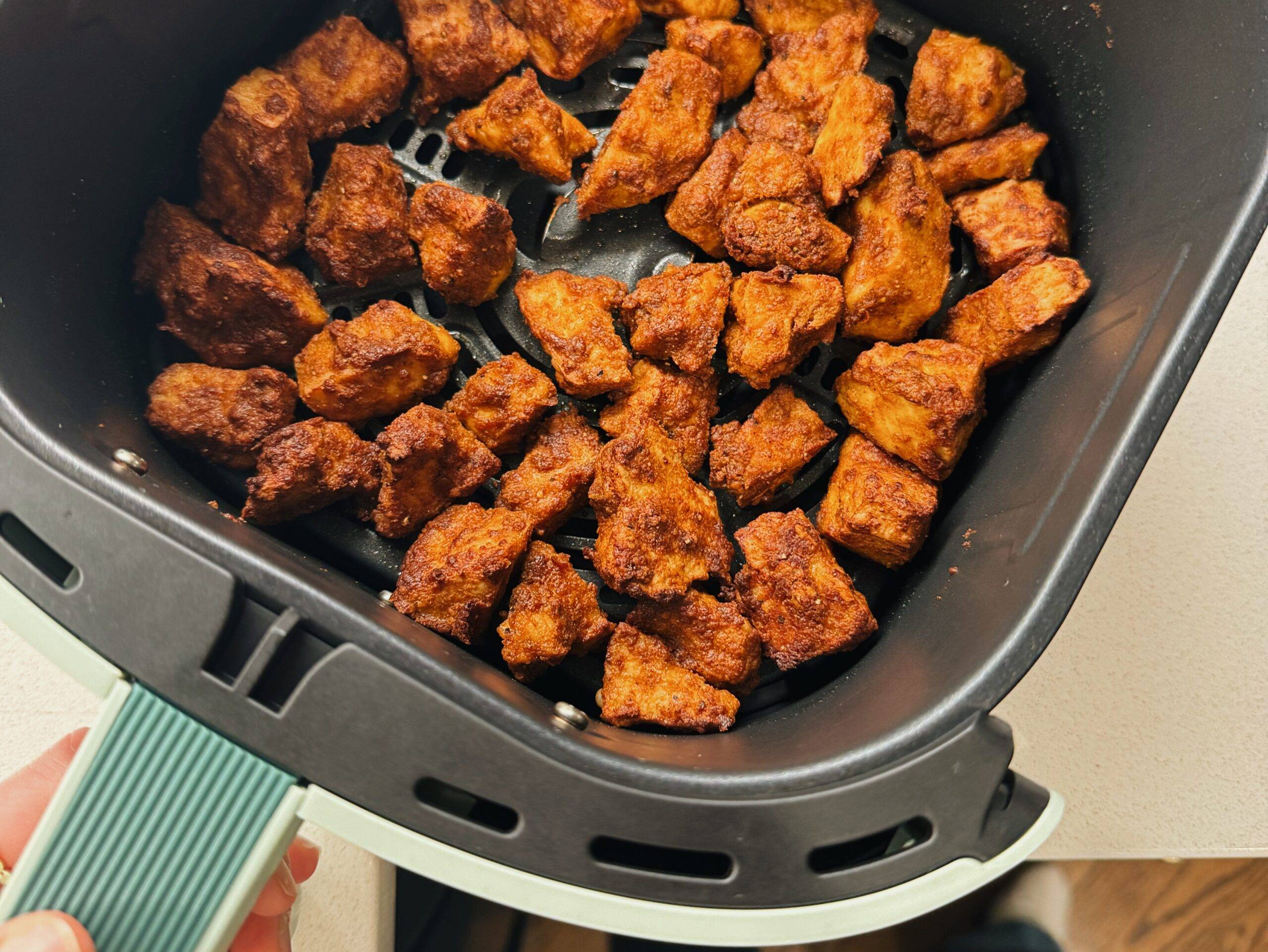 Air fried tofu in an air fryer basket.