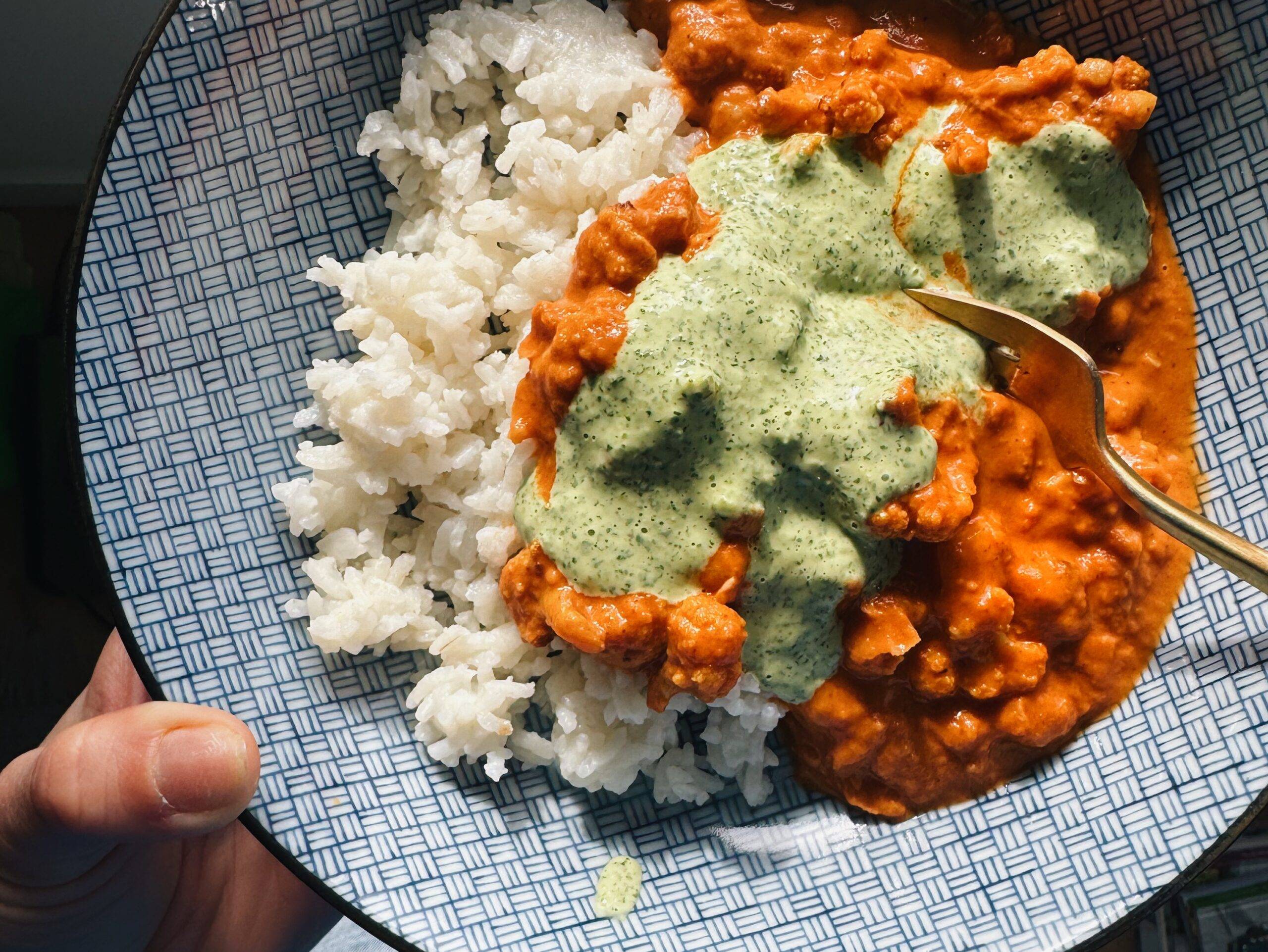 Butter cauliflower and chickpeas in a bowl with mint sauce on top.