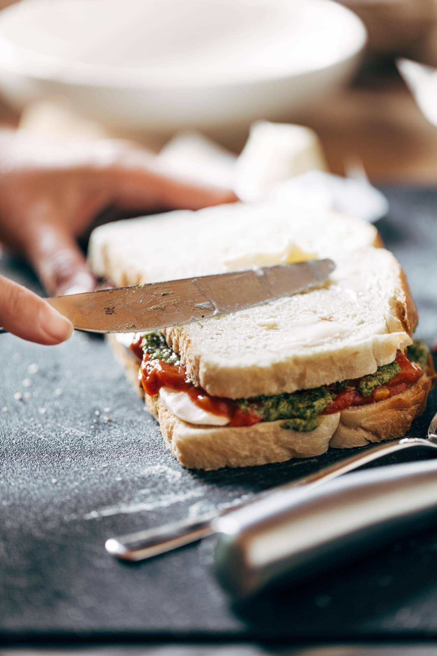 Caprese Grilled Cheese being cut with a knife.