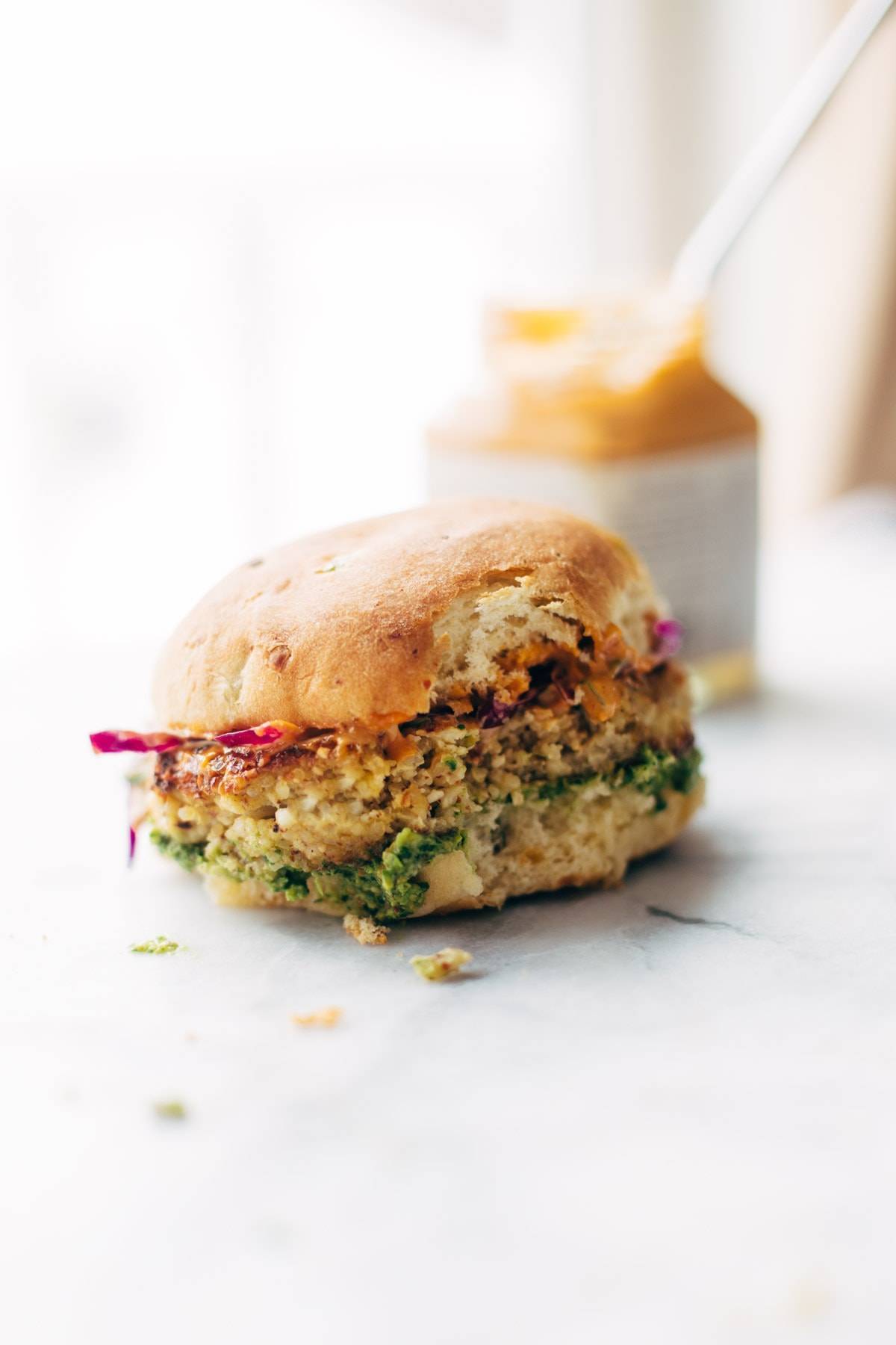 A cauliflower burger with a bite taken out.