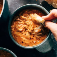 White hand dipping bread into soup