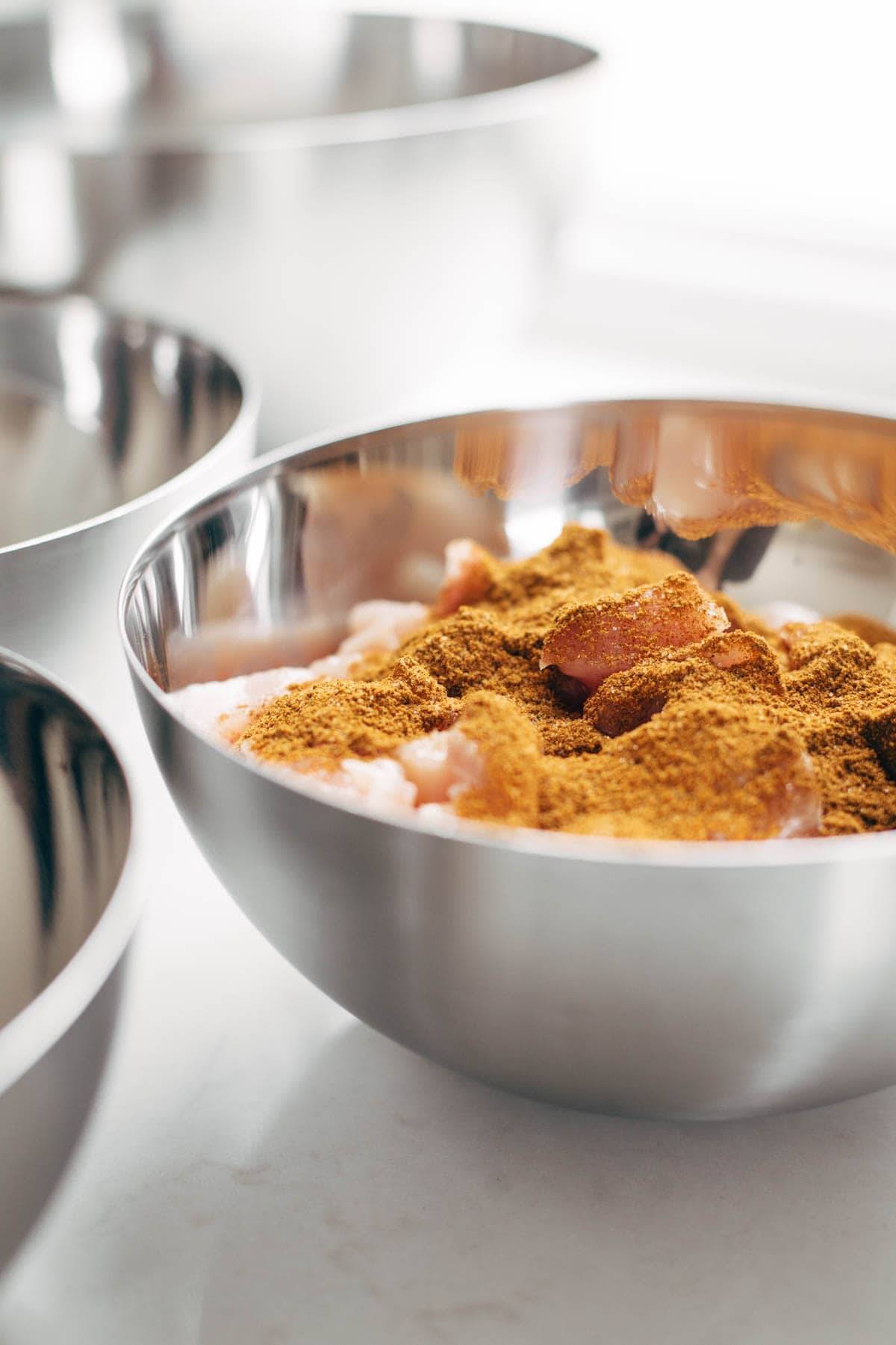 Chicken with seasonings for Meal Prep in a silver bowl. 