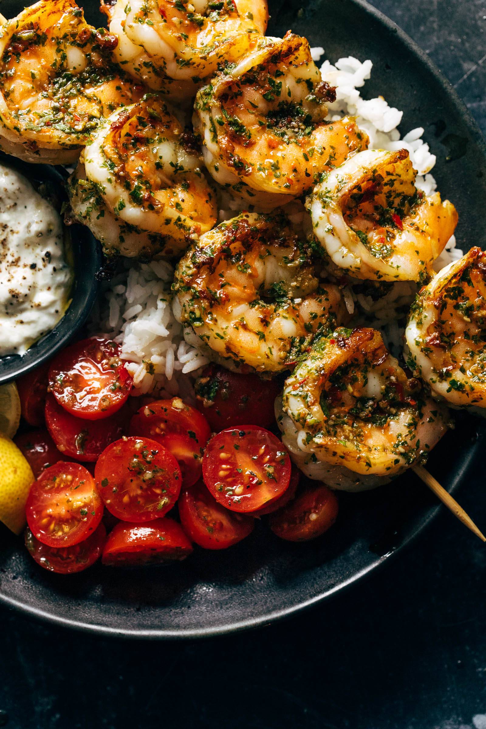 Chimichurri shrimp in a bowl with rice and tomato salad.