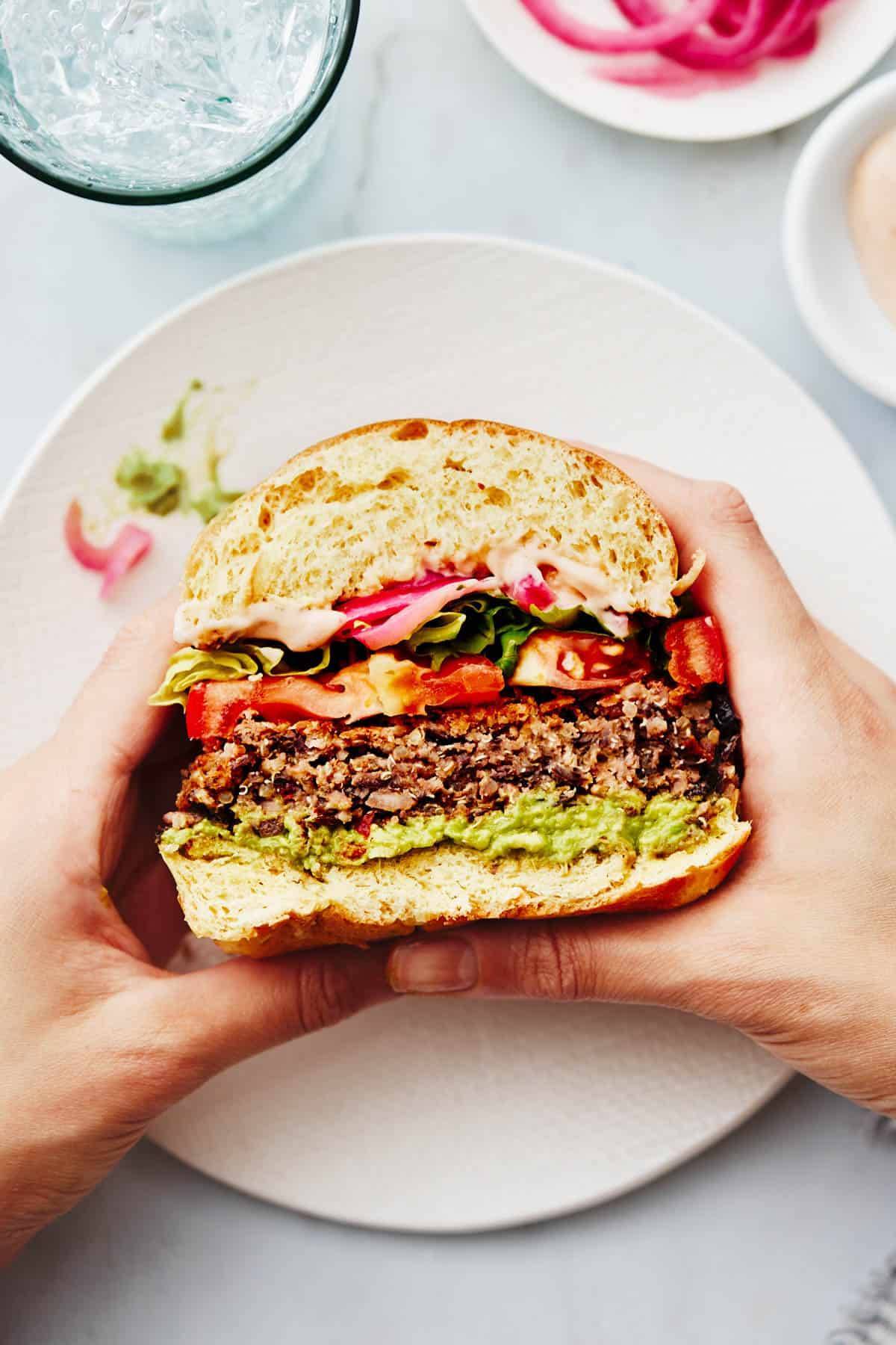 Quinoa burger in hands cut in half.