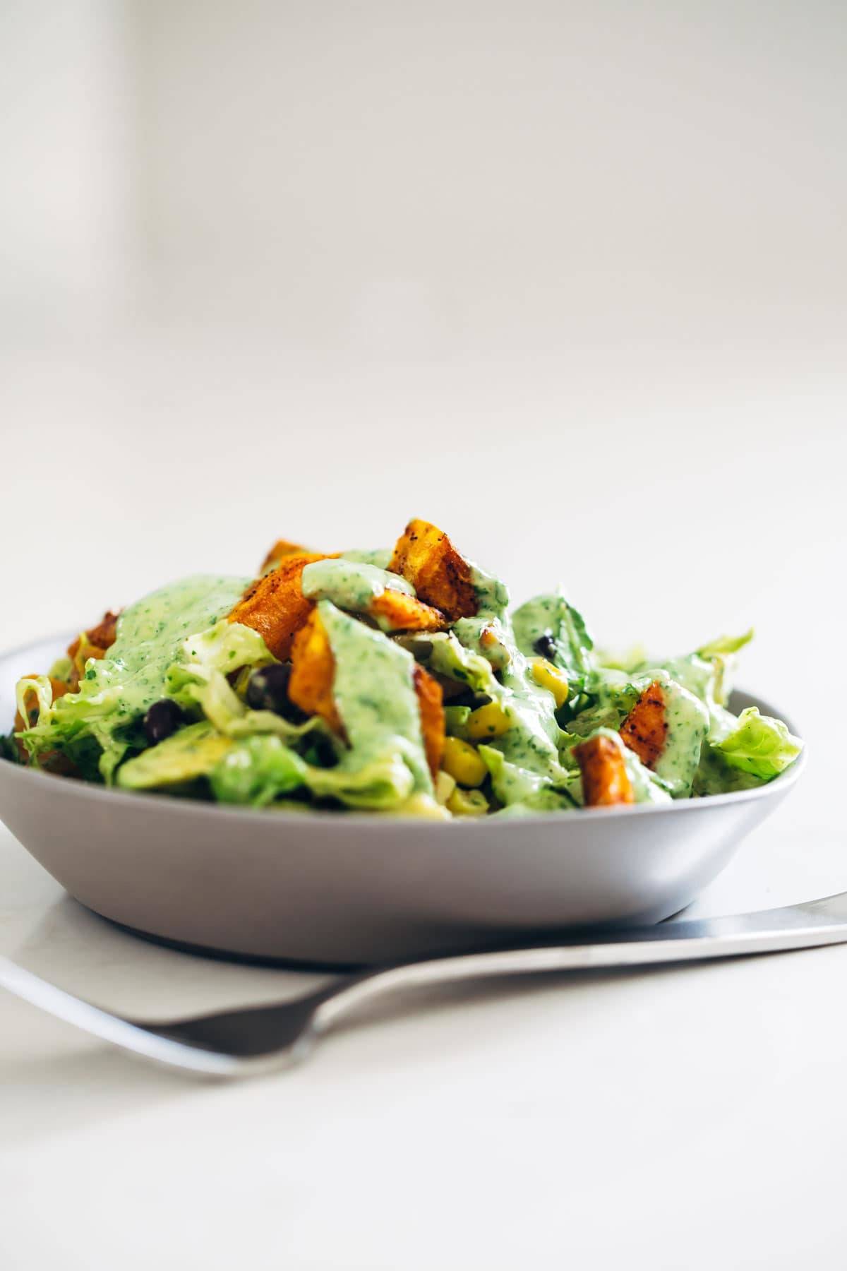 This healthy Spicy Southwestern Salad recipe has roasted sweet potatoes, black beans, corn, lettuce, and creamy avocado dressing! | pinchofyum.com