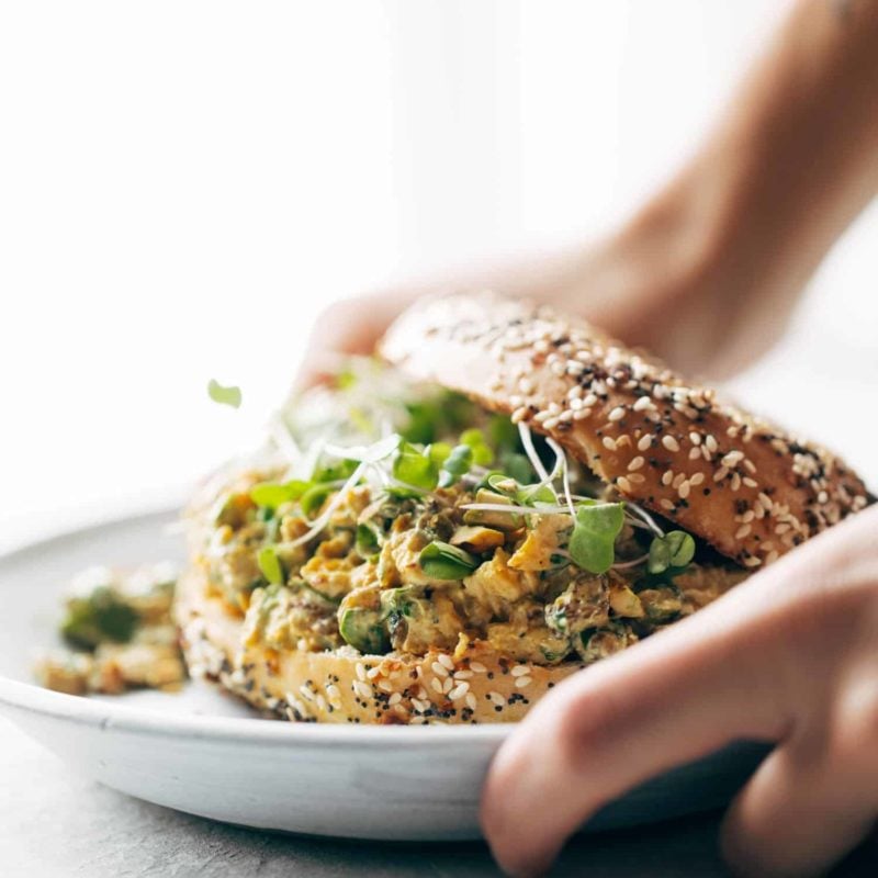 A person placing down a plate with a sandwich on it.