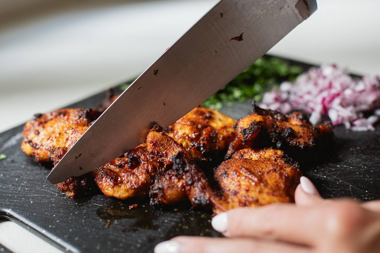 Slicing browned chicken on a cutting board.