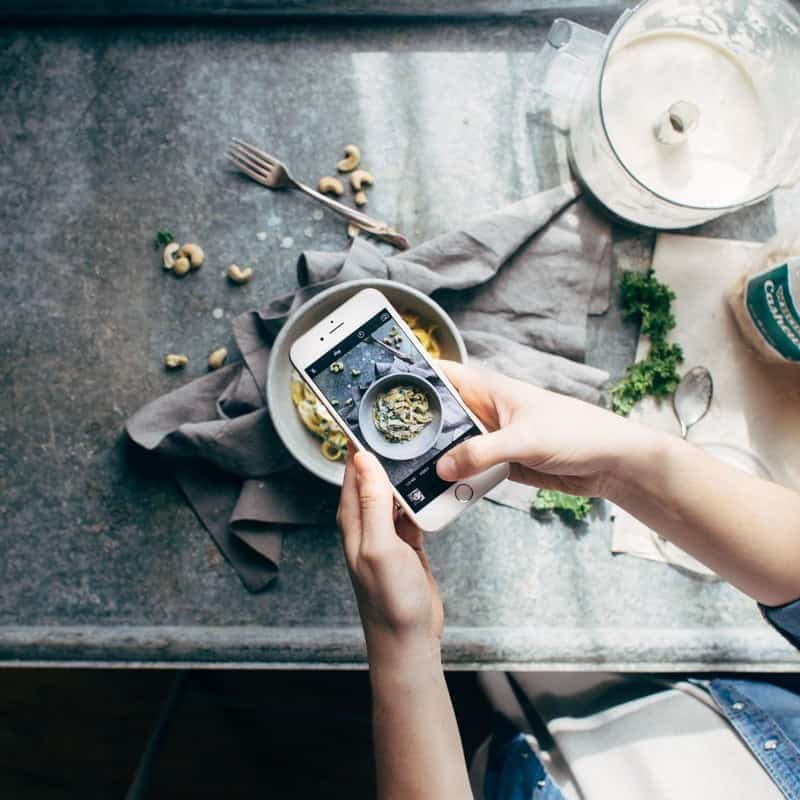 Person holding an iPhone taking a picture of food.