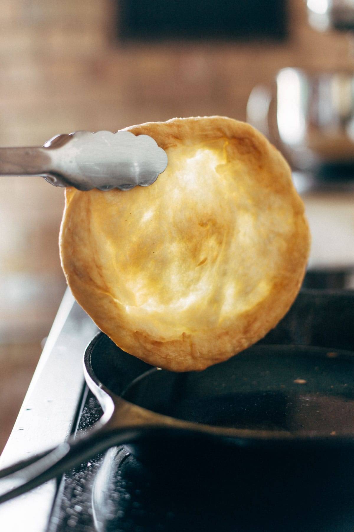 Frying pizza dough in a cast iron pan.