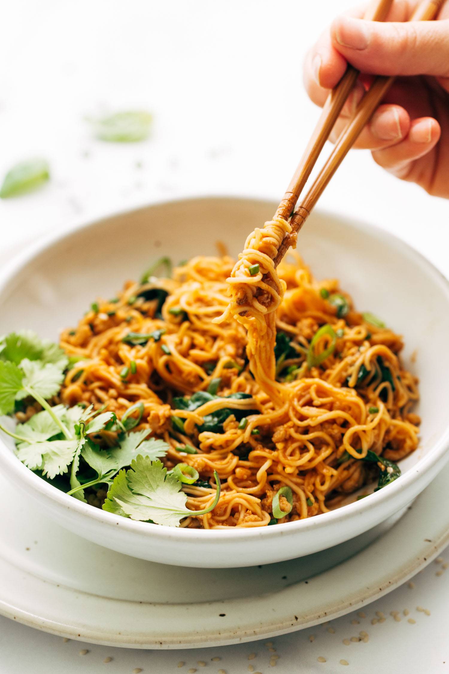 Lifting noodles out of a bowl with chopsticks.