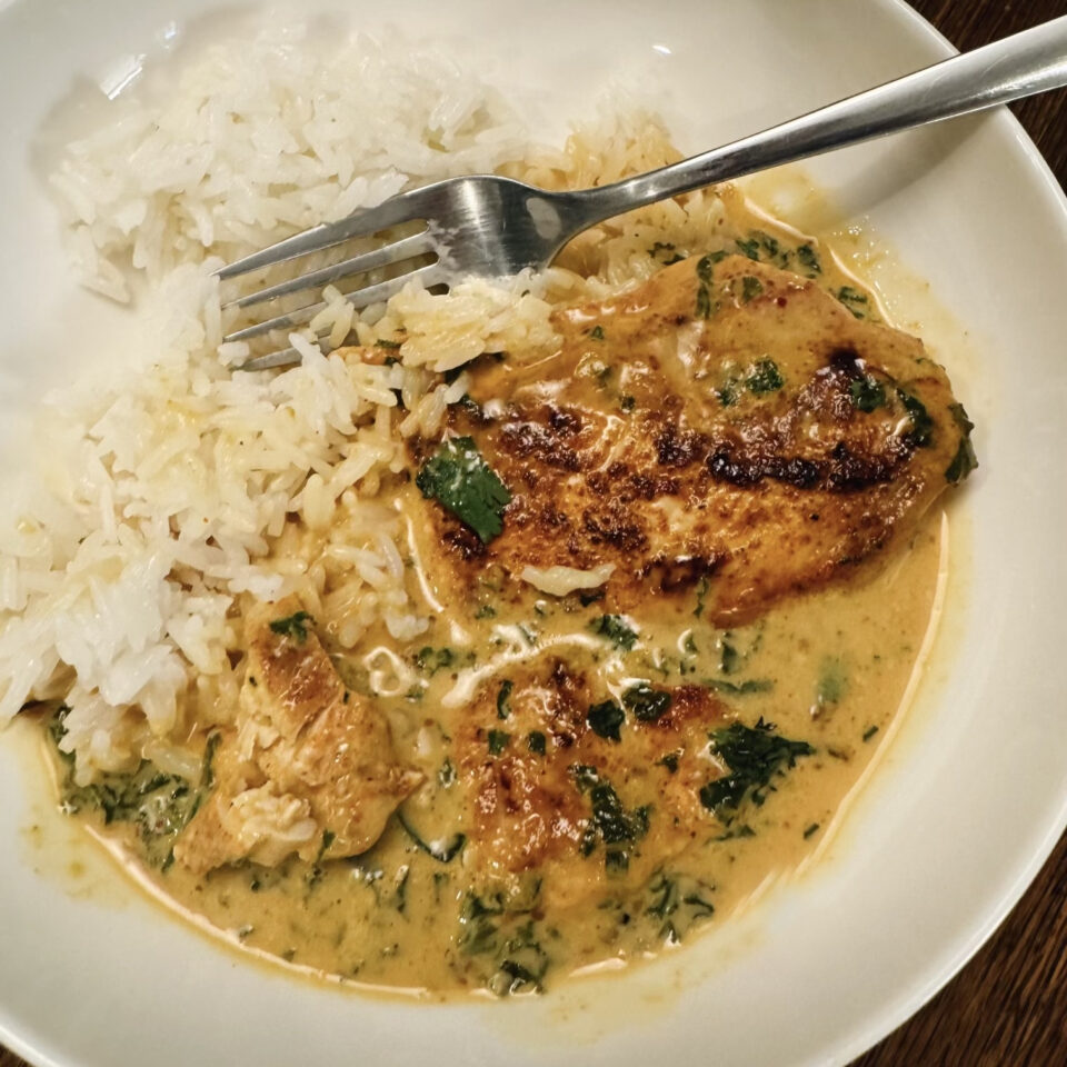 Bowl of chicken with coconut kale and white rice.