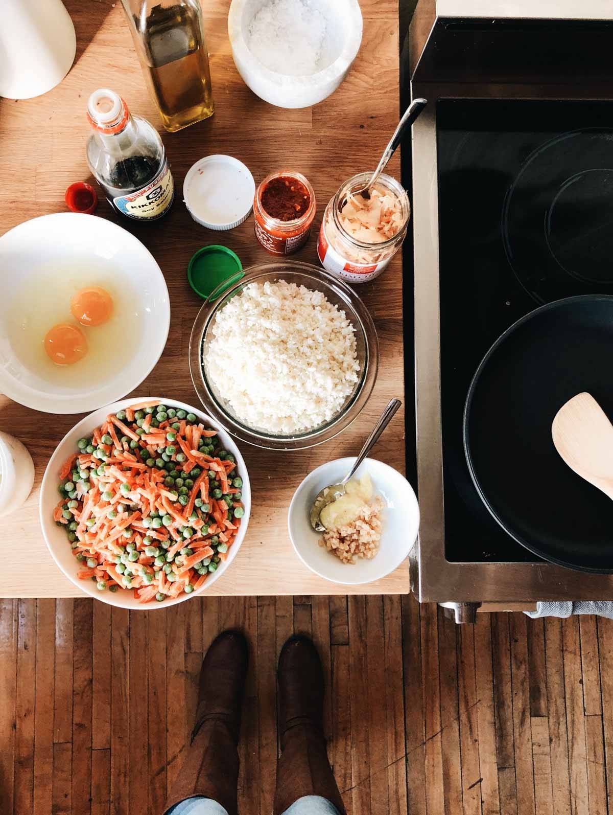 Rice, eggs, carrots and peas on a counter.