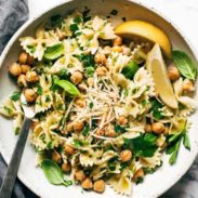 Pasta tossed with greens and cheese with lemon wedges.