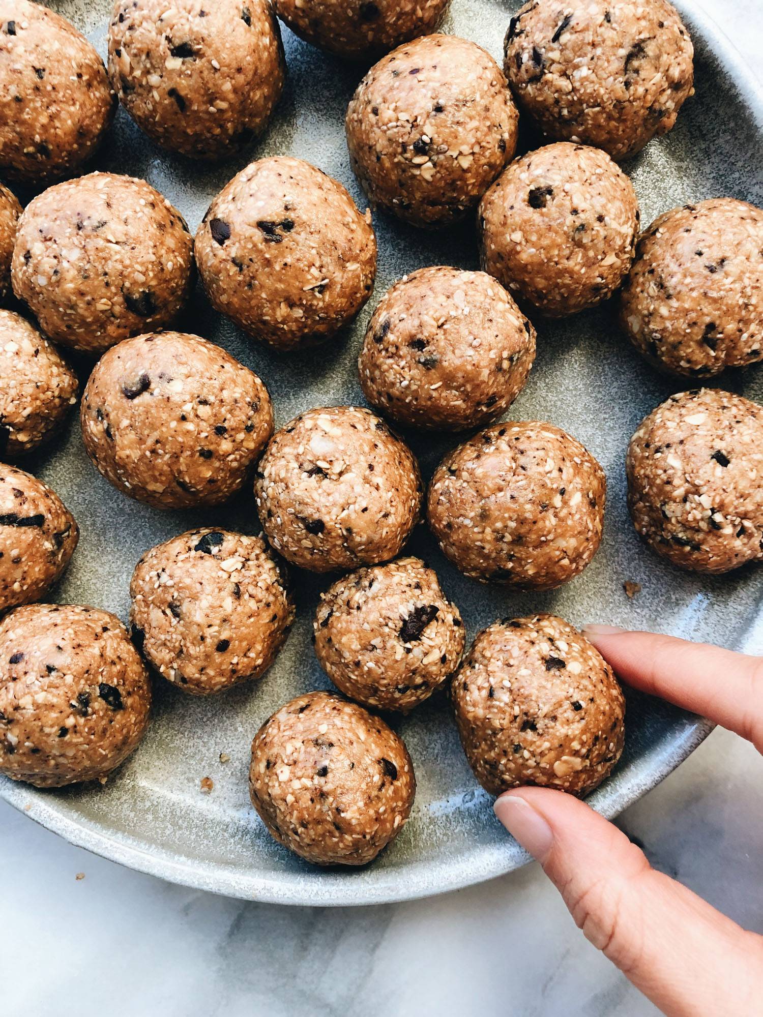 Pecan pie balls being picked up for a snack from a rustic bowl.