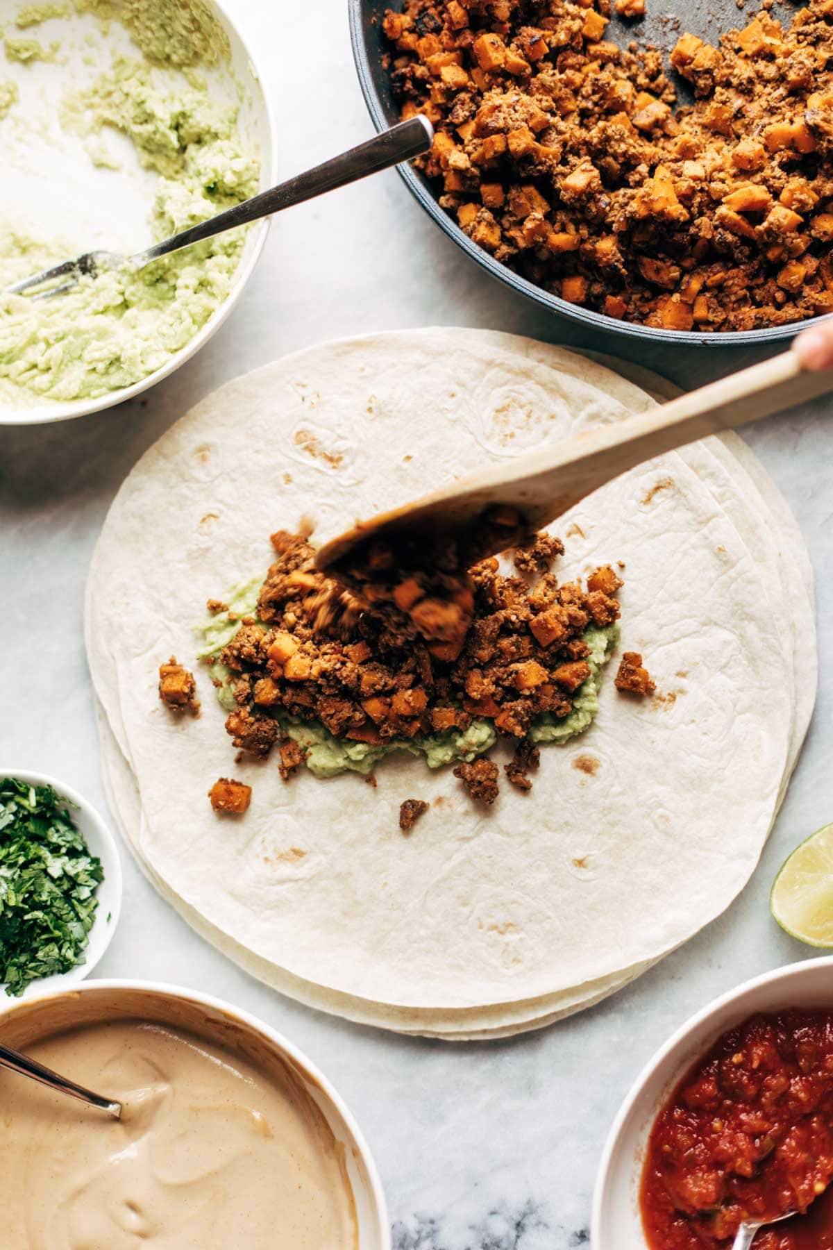 Adding cauliflower walnut taco meat to tortilla.