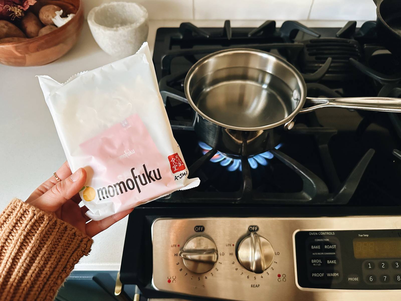 A package of Momofuku noodles next to a pot of water.