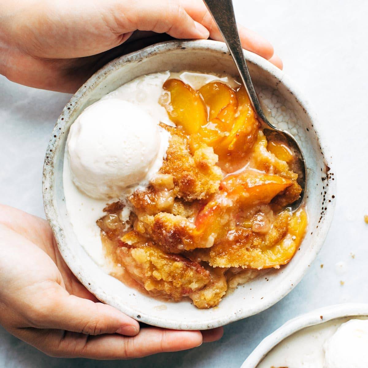 Peach cobbler in a bowl with ice cream.