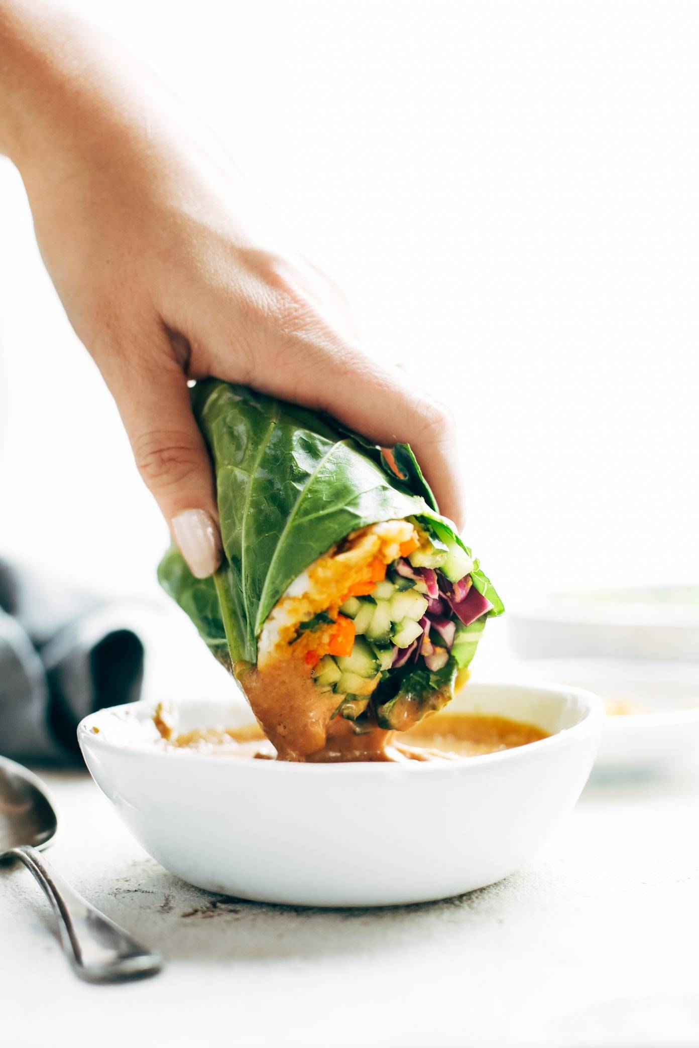 Detox Rainbow Roll-Ups dipped in peanut sauce.