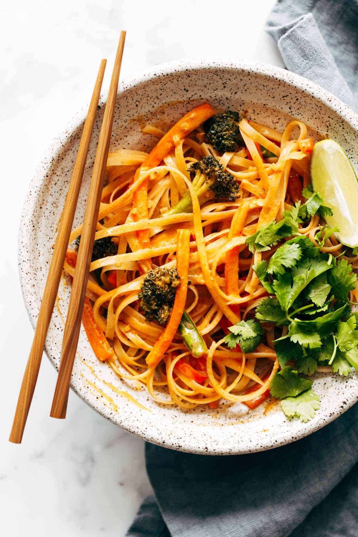 Red curry noodles in a bowl with chopsticks.