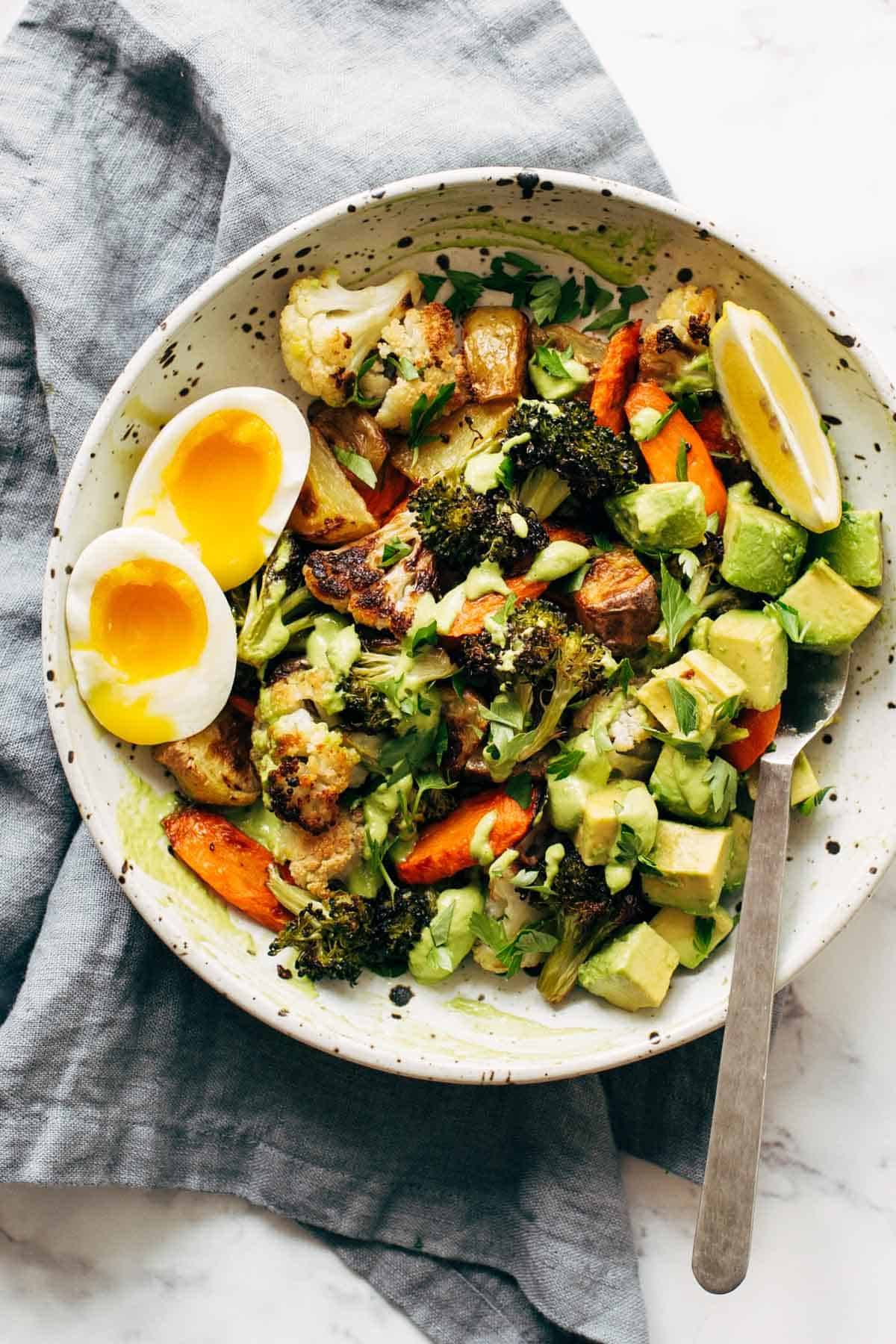 Roasted Vegetable Bowls with Green Tahini and a side of egg and a spoon in the bowl.