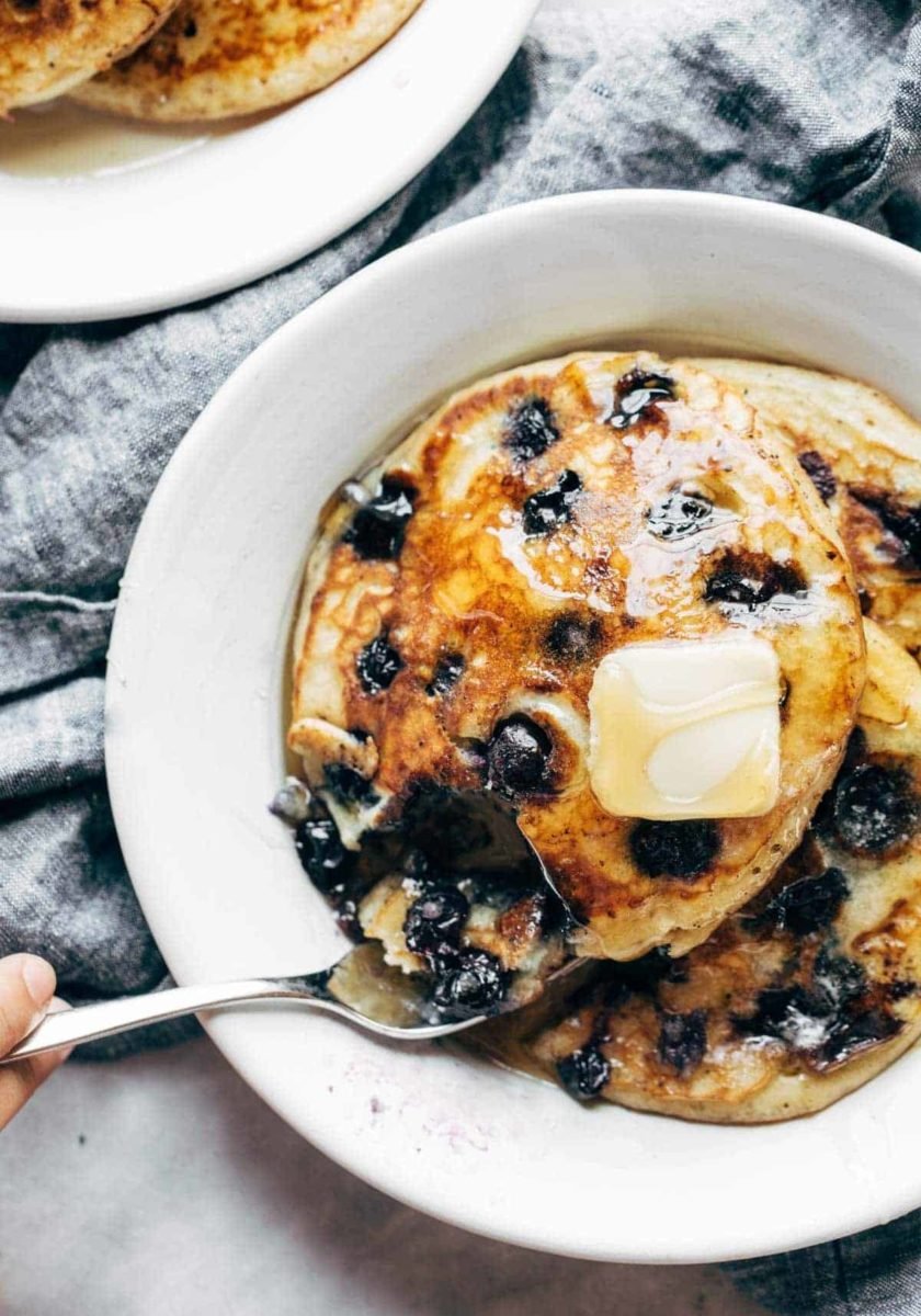 Blueberry pancakes on a plate with syrup and butter.