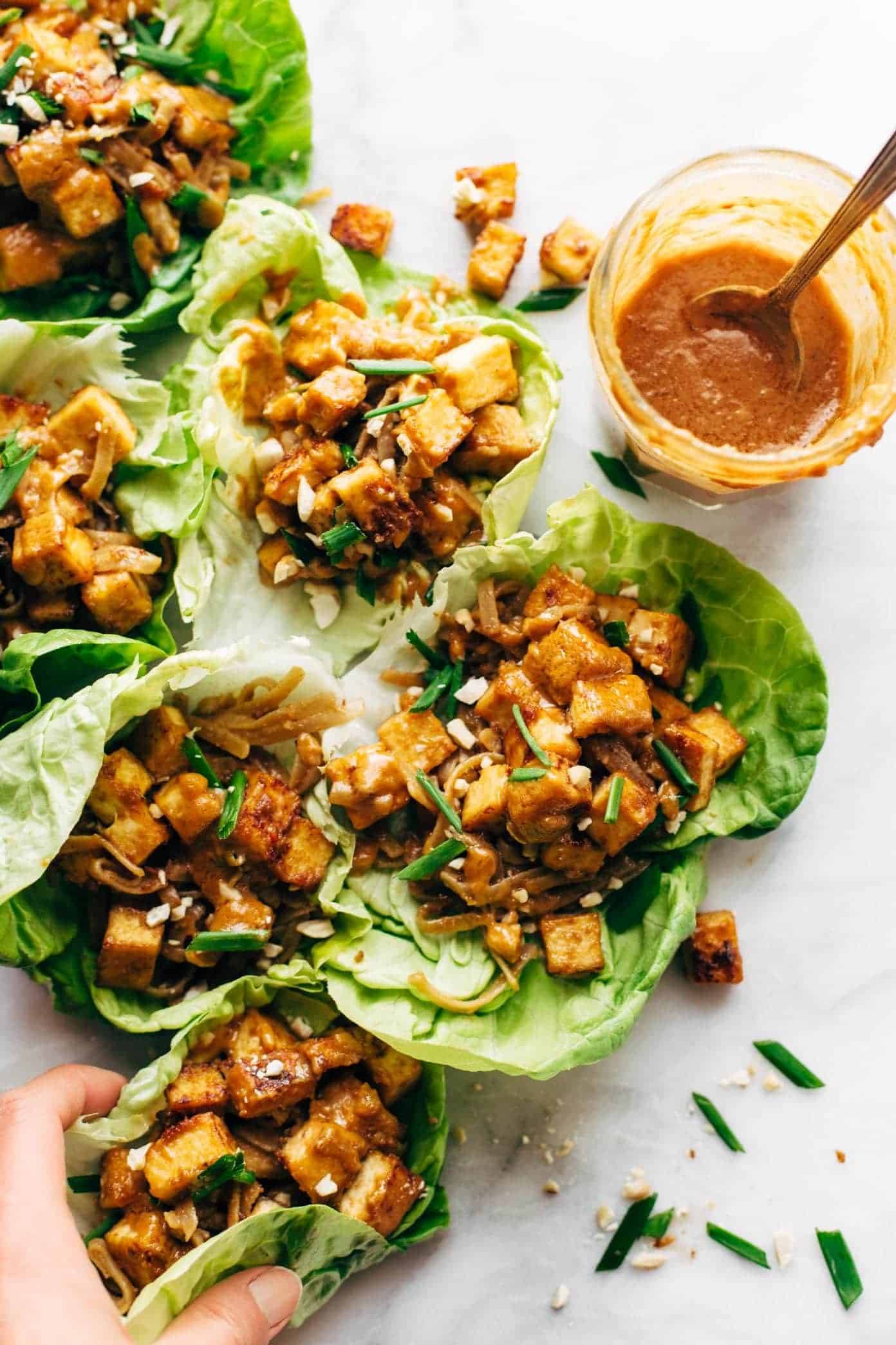 Tofu lettuce wraps on table with jar of sauce.