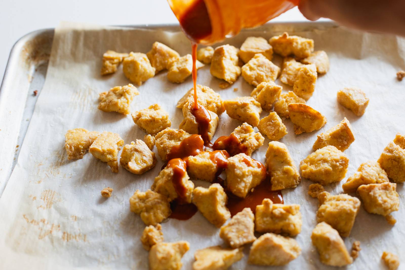 Pouring sauce on baked crispy tofu.