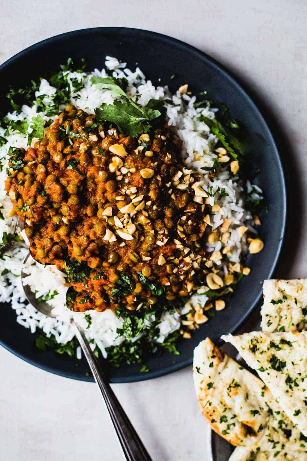 Red curry lentils on plate with rice and naan.